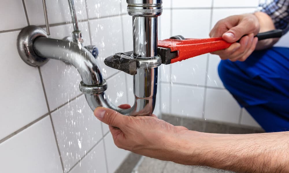 Mains saississant un tuyau de canalisation avec une pince multiprise