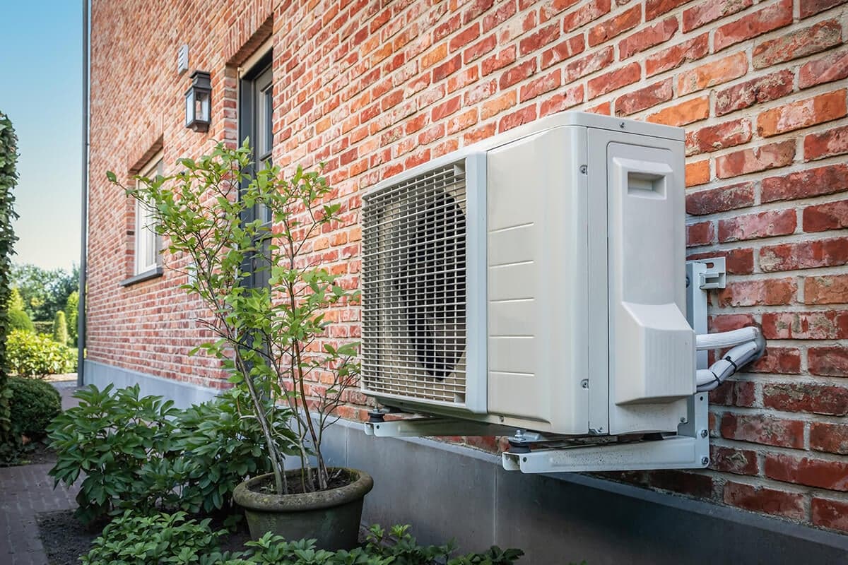 Pompe à chaleur installé à l exterieur d'une maison sur un mur en brique